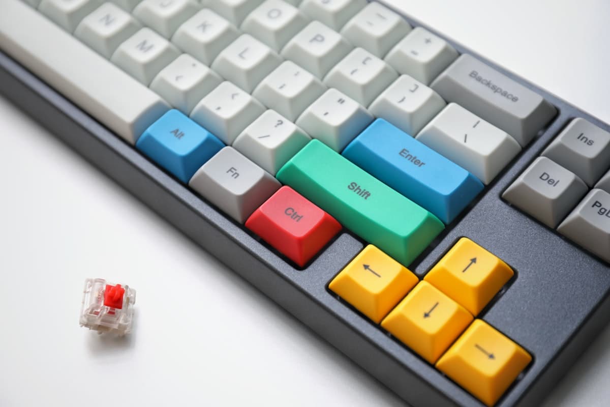 A mechanical keyboard with bright keycaps beside a loose switch